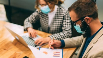Balancing the Importance of Data & Metrics While Avoiding Analysis Paralysis coworkers in masks reviewing data analytics