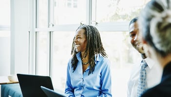 Woman happily working on laptop with other colleagues